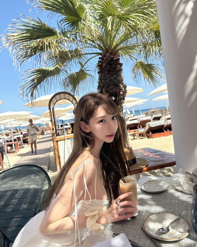 照片中可見Cammi換上多套服裝，分別是一套藍白條紋的比堅尼、白色吊帶連身裙、白色長袖防曬衣，在沙灘上擺出不同誘人姿勢。