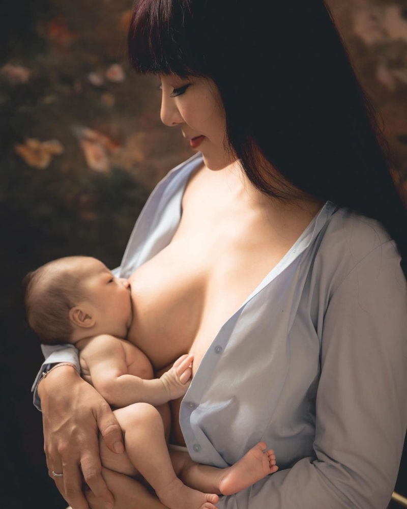 李宓穿上一件淺藍色襯衫，不過就將扣子解開露出35F傲人上圍，并將剛出生的雙胞胎女兒放在大腿上喂母乳及遮住重點部位。