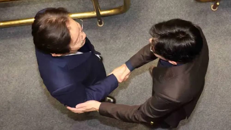 南韓國會投票解除戒嚴后，韓國朝野兩大政黨黨魁在現場握手。 李在明（左）、韓東勛（右）。 中國新聞網截圖