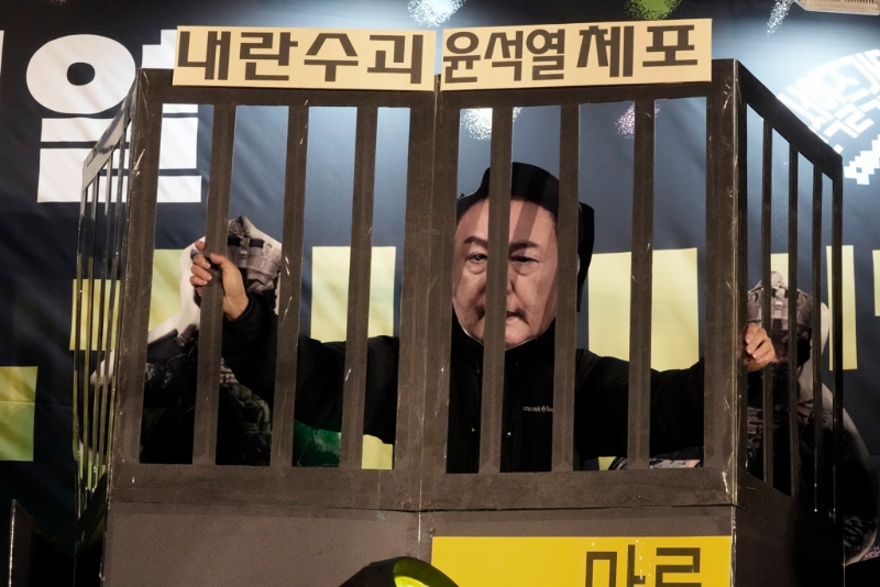 南韓首爾國會外要求尹錫悅下臺的群眾，11日晚間戴上尹錫悅面具置身標明「逮捕叛亂首腦尹錫悅」的牢籠，藉此表達對于尹錫悅的強烈不滿情緒。（美聯社）