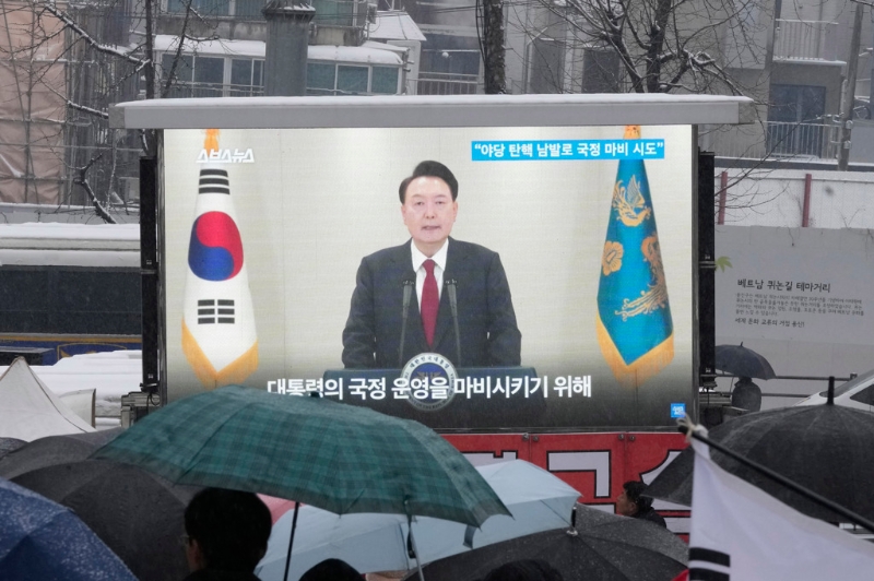 南韓總統尹錫悅因戒嚴遭國會彈劾停職，數度拒絕檢方傳喚調查?？偨y官邸外的挺引群眾5日圍在電視熒幕前收看新聞報導。（資料照／美聯社）