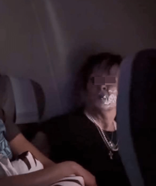 另一張出現在當地媒體的照片，婦人被綁在座位上，嘴巴封上透明膠紙，雙目怒瞪著坐在鄰座看守她的空姐。.png