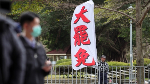 圖為民眾在民進黨中央黨部樓下高舉旗幟，要求黨主席賴清德對大罷免表態。